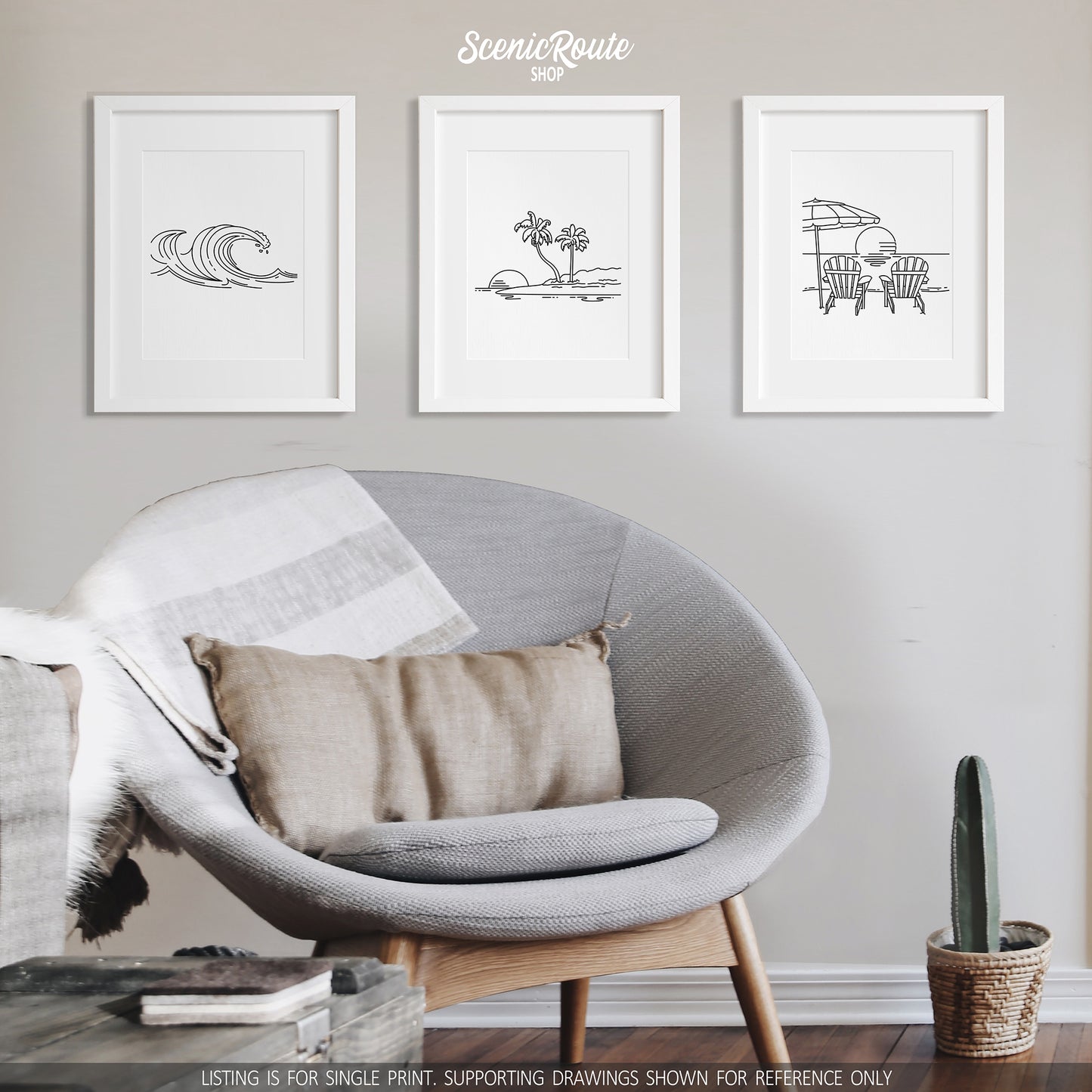 A group of three framed drawings on a white wall above a round chair. The line art drawings include Waves, an Island, and Adirondack Beach Chairs