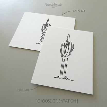 Two line art drawings of a Saguaro Cactus on white linen paper with a gray background.  The pieces are shown in portrait and landscape orientation for the available art print options.