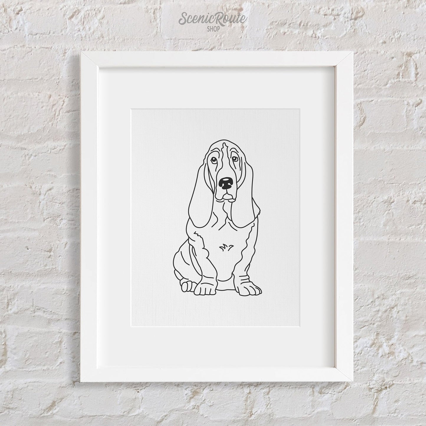 A framed line art drawing of a Basset Hound dog on a white brick wall