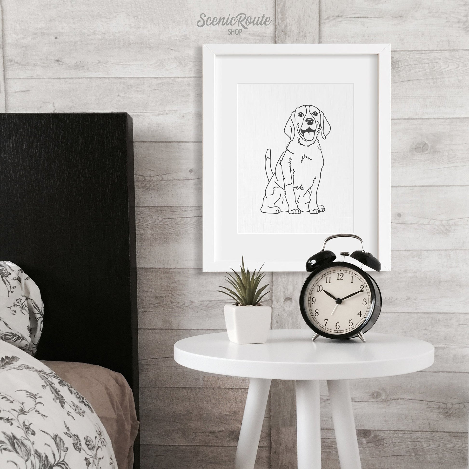 A framed line drawing of a Beagle dog hung above a table next to a bed