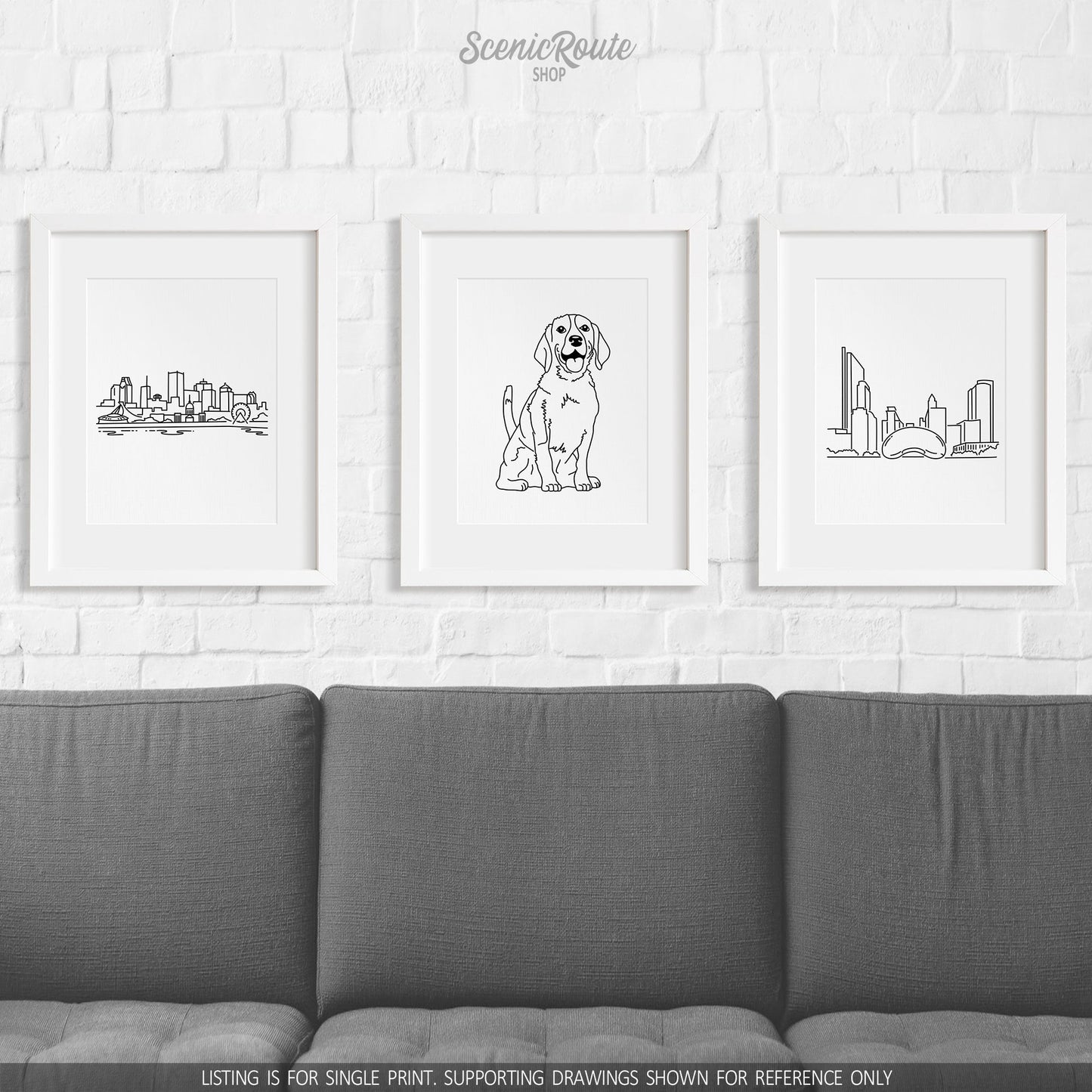 A group of three framed drawings on a brick wall hung above a couch.  The line art drawings include the Montreal Canada Skyline, Beagle Dog, and the Cloudgate Bean Sculpture in Chicago