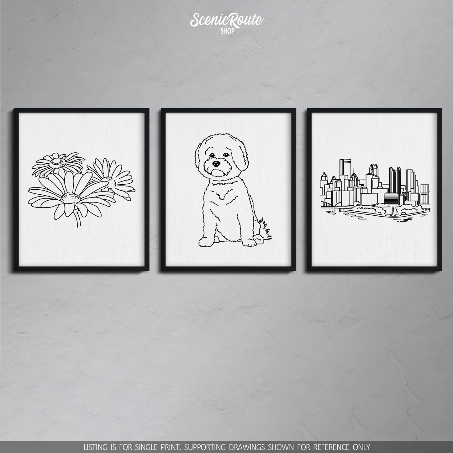 A group of three framed drawings on a gray wall. The line art drawings include daisies, a Bichon Frise dog, and the Pittsburgh Skyline