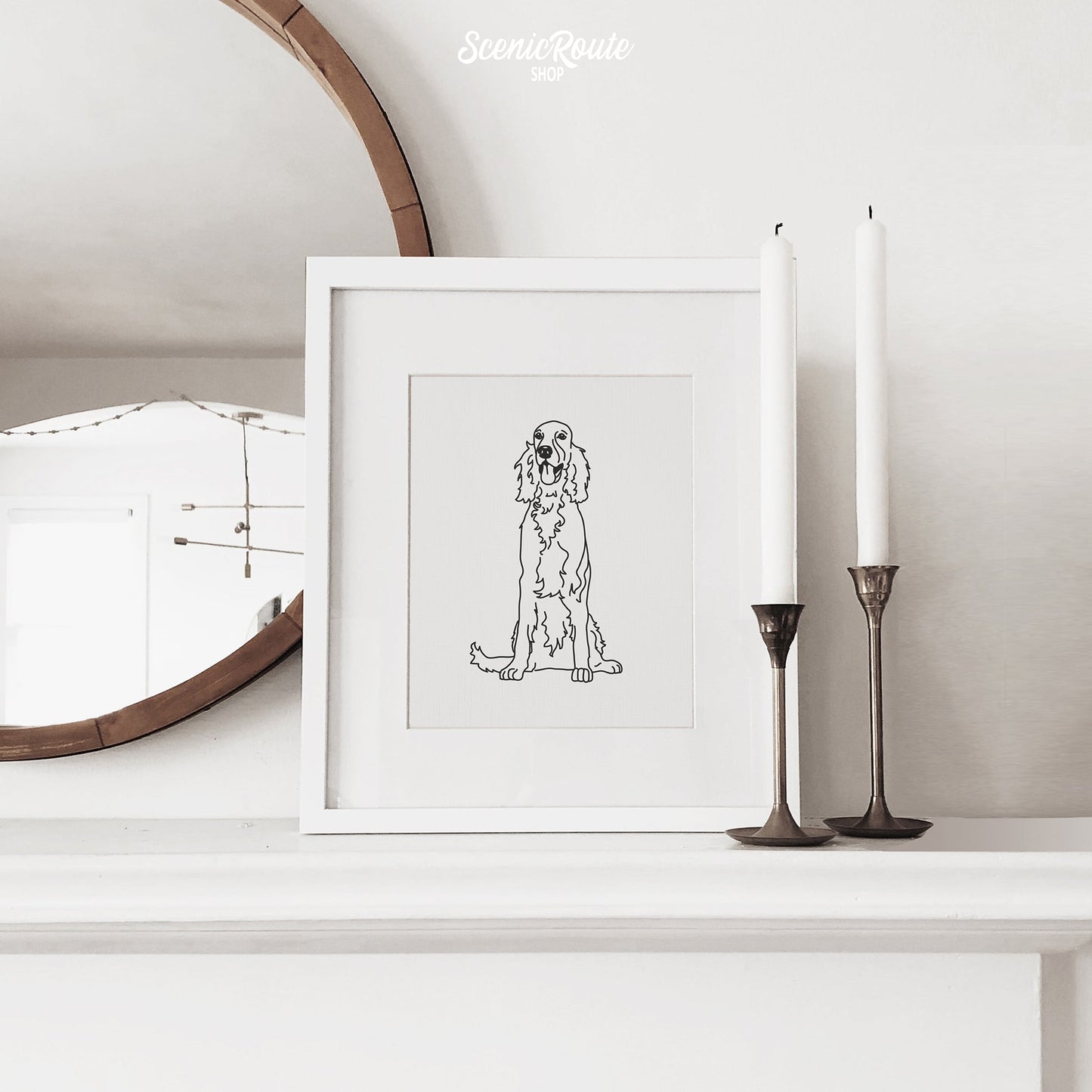 A framed line art drawing of an Irish Setter dog on a mantle with candles and a mirror