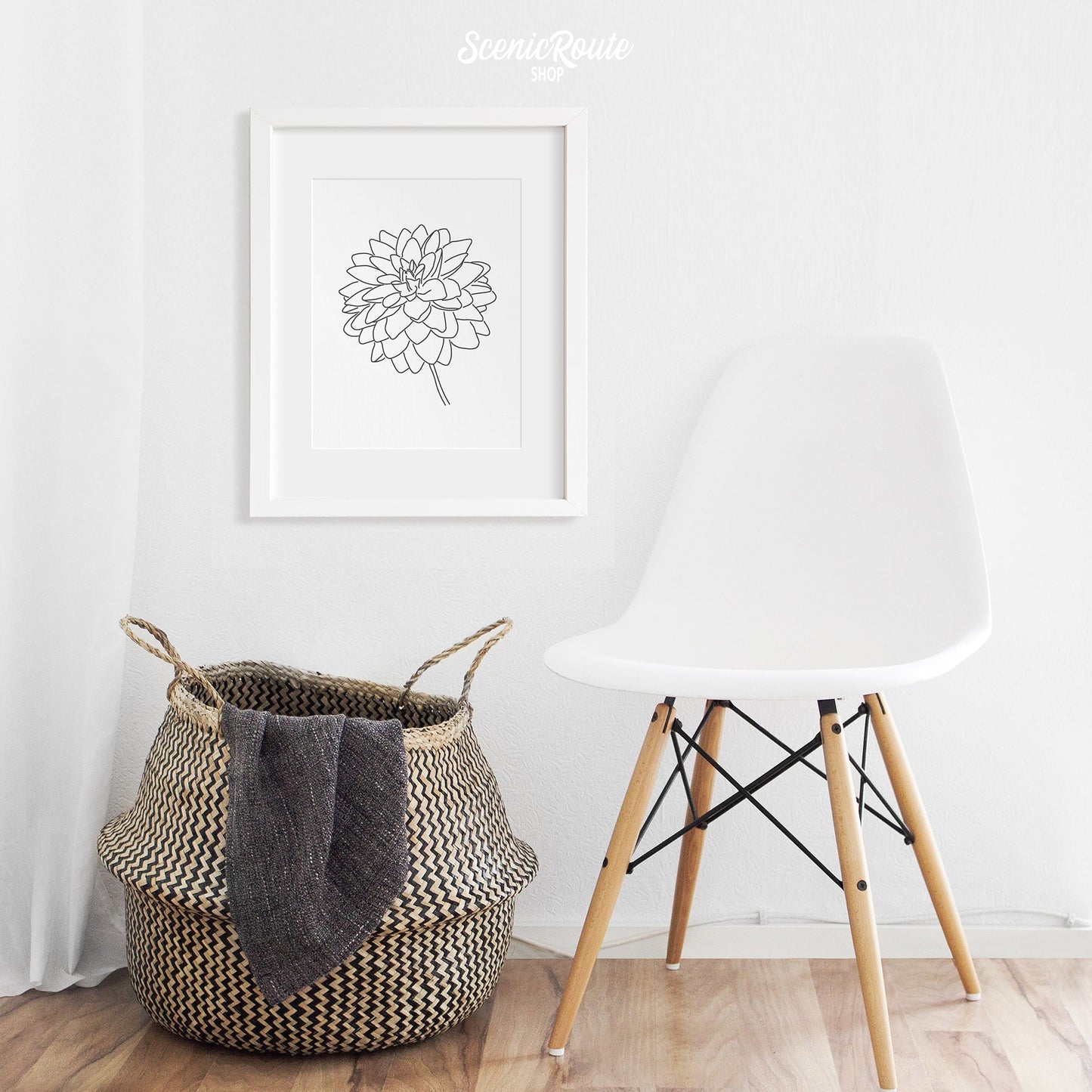 A framed line art drawing of a Dahlia Flower above a basket and chair