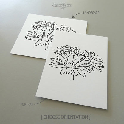 Two line art drawings of a Daisy Flower on white linen paper with a gray background.  The pieces are shown in portrait and landscape orientation for the available art print options.