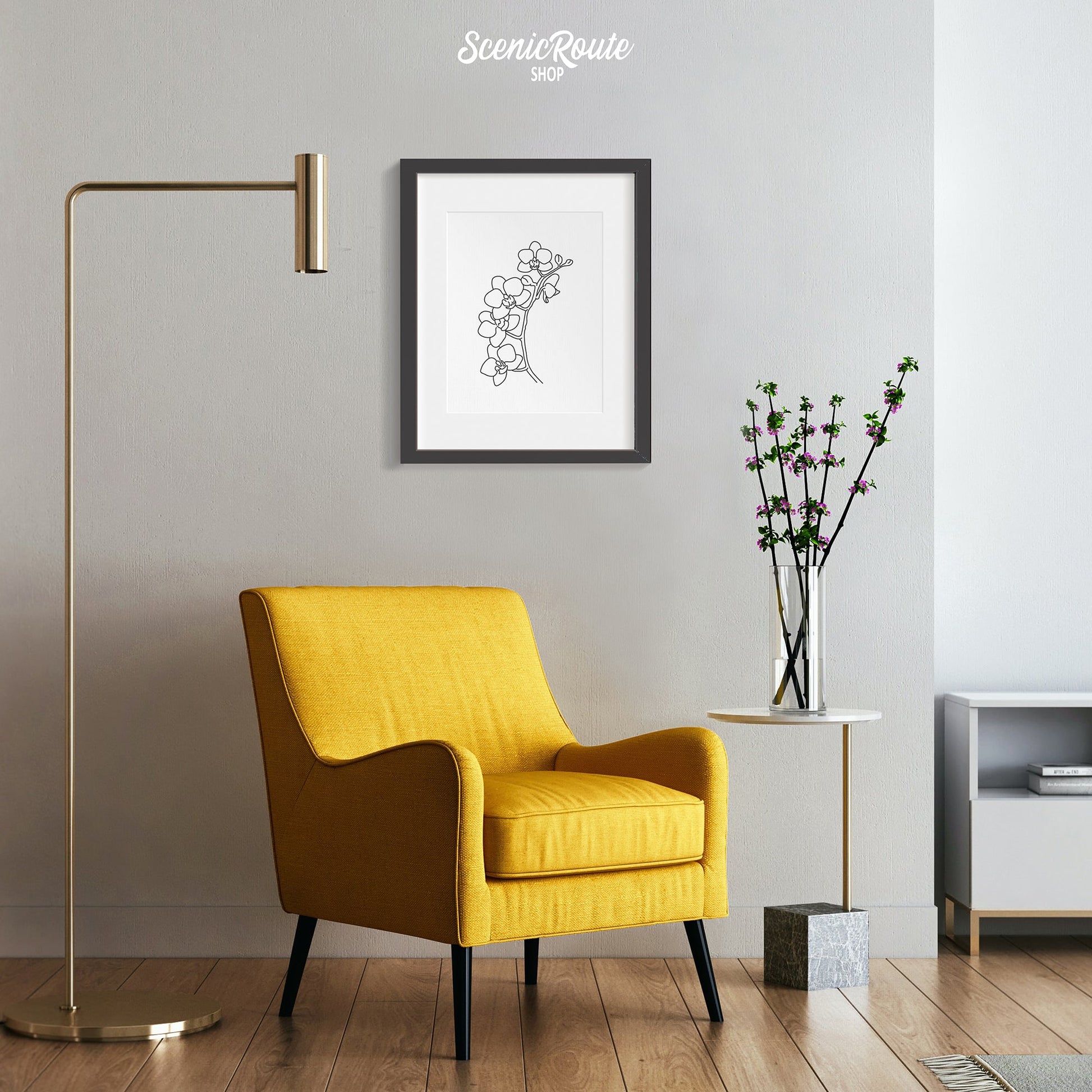 A framed line art drawing of a Orchid Flower above a yellow chair with a lamp