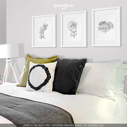 A group of three framed drawings on a white wall above a bed. The line art drawings include the Orchid Flower, Rose Flower, and Daisy Flowers