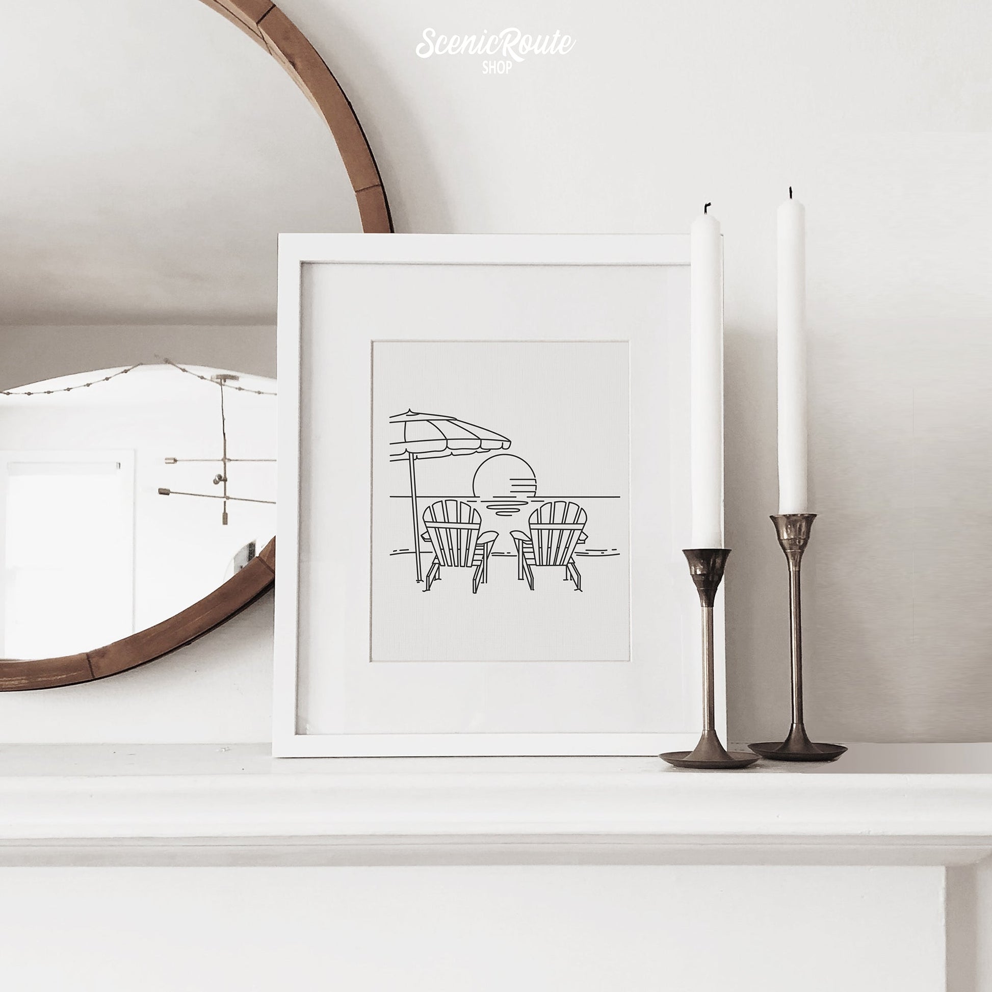 A framed line art drawing of Adirondack Beach Chairs on a mantle with candles and a mirror