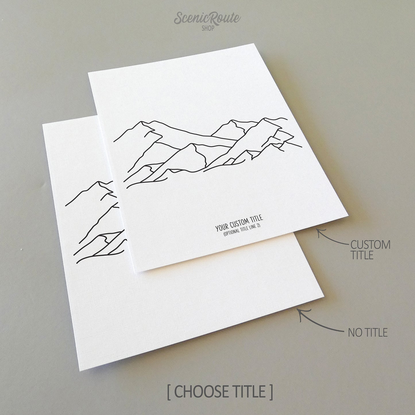 Two line art drawings of a mountain range on white linen paper with a gray background. The pieces are shown with “No Title” and “Custom Title” options for the available art print options.