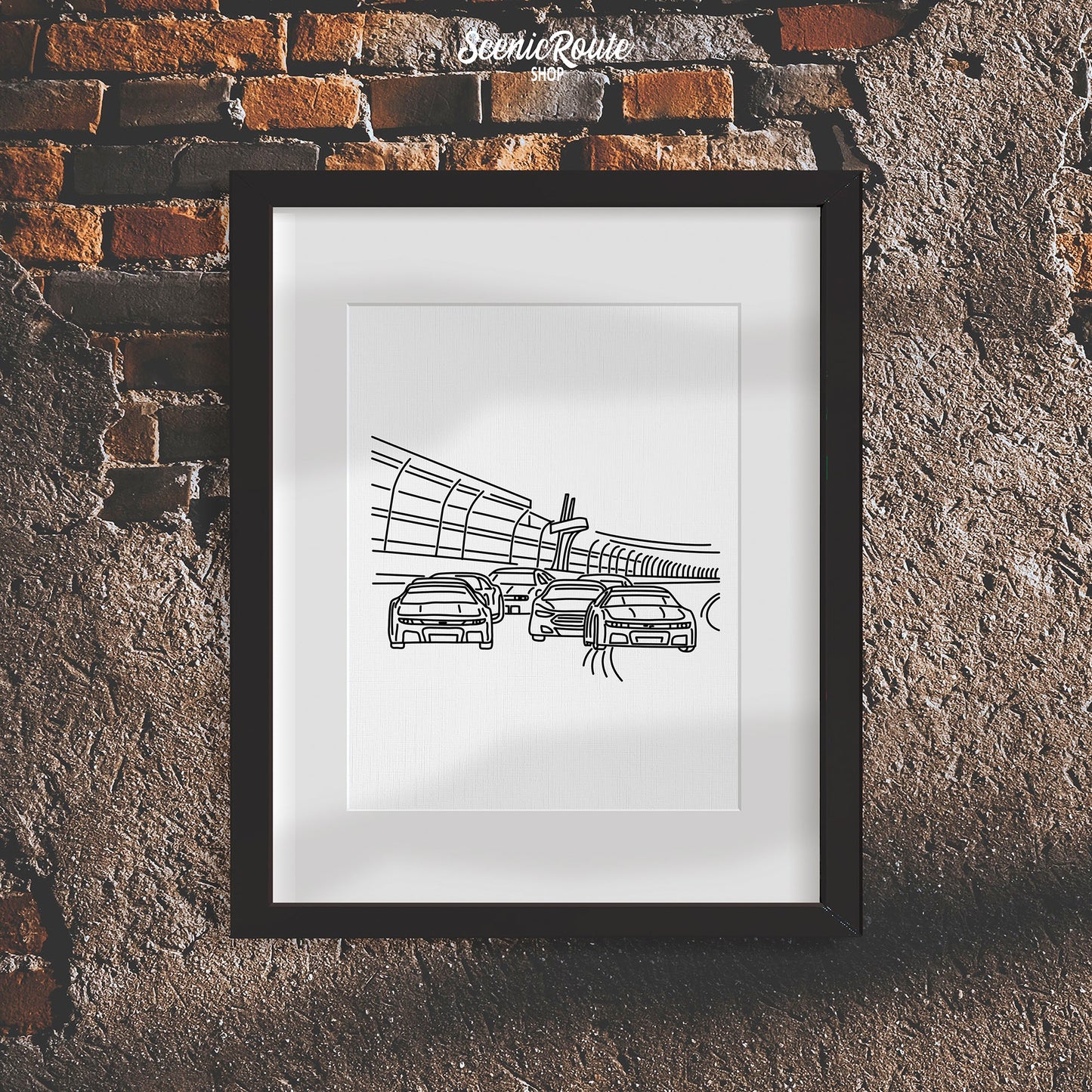 A framed line art drawing of Nascar on a rough brick wall