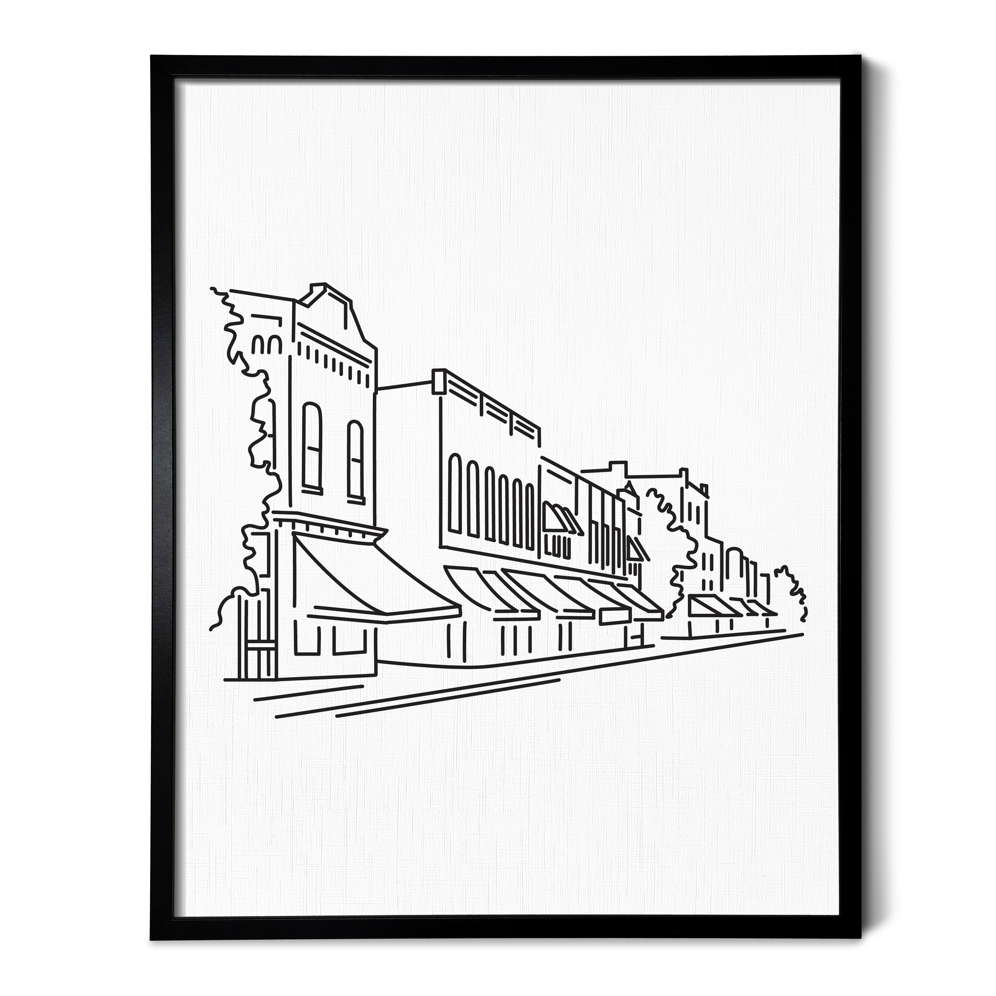 A line art drawing of a small downtown street on white linen paper in a thin black picture frame
