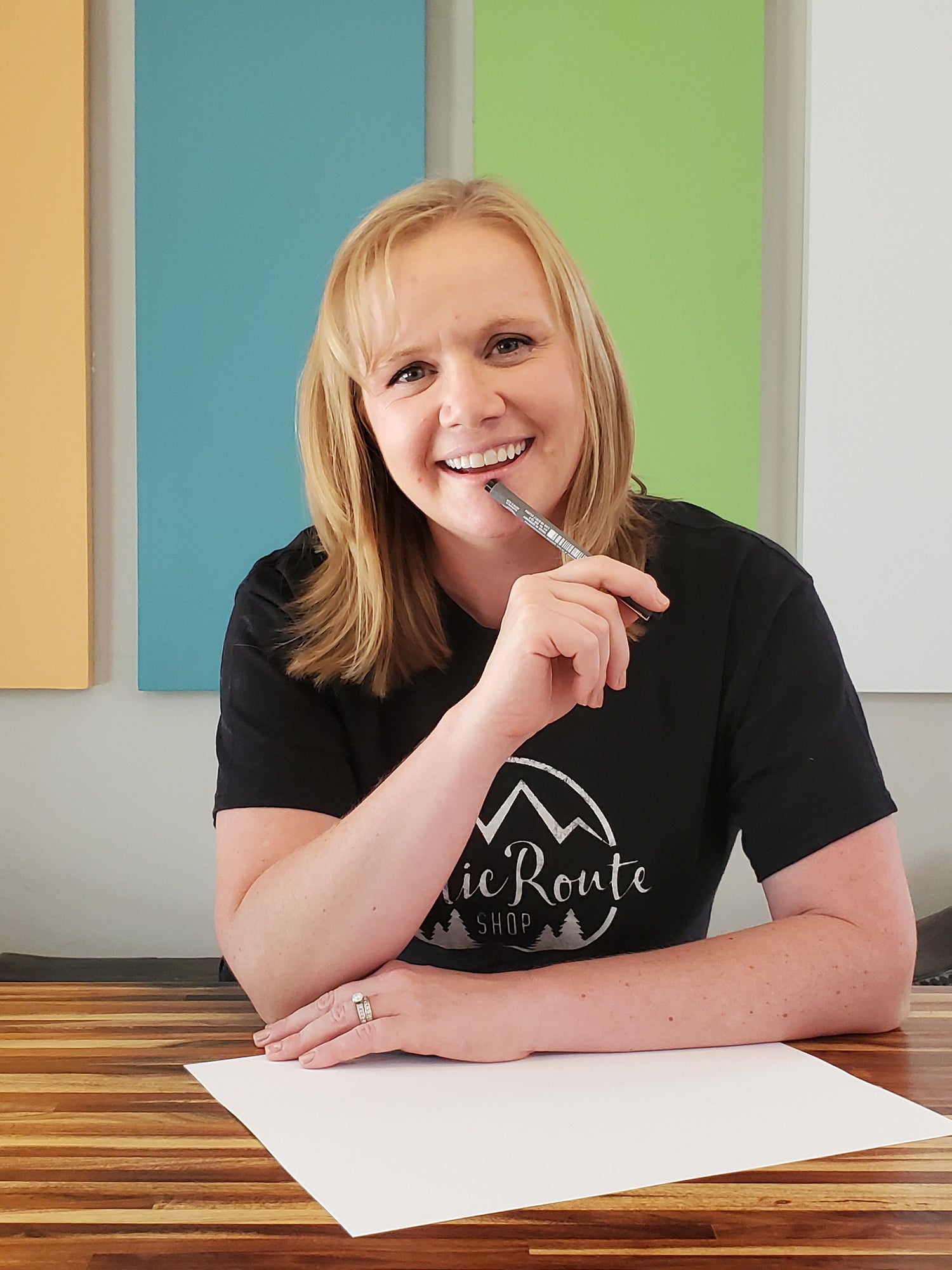 A photo of a woman smiling with a pen and paper