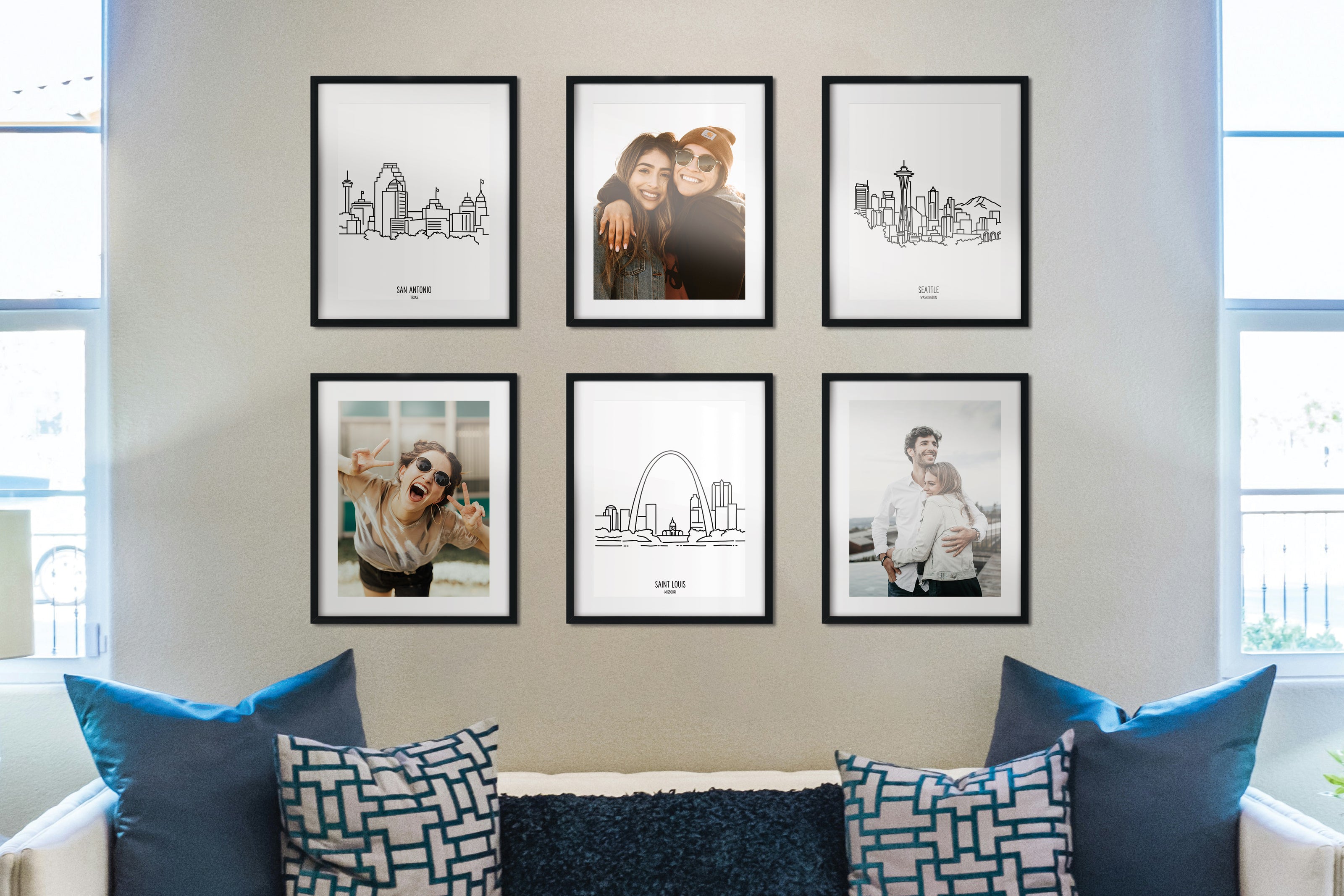 A group of six framed drawings of skylines and photos on a wall above a couch with pillows.