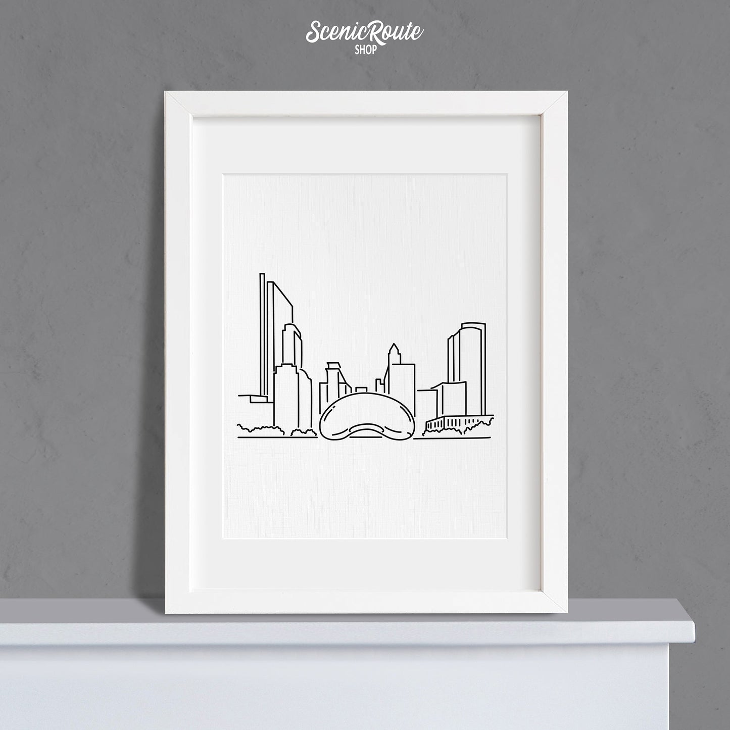 A framed line art drawing of the Chicago Bean Sculpture on a mantle