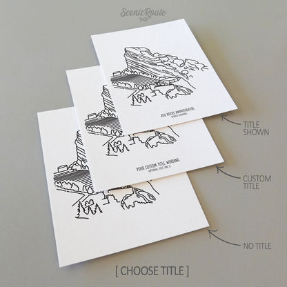 Three line art drawings of the Denver Red Rocks Amphitheatre in Colorado on white linen paper with a gray background.  The pieces are shown with title options that can be chosen and personalized.