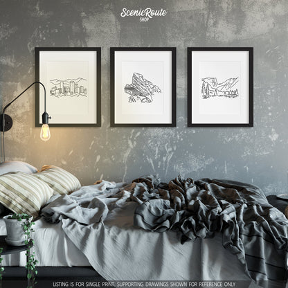 A group of three framed drawings on a white wall above a messy bed. The line art drawings include the Denver Skyline, Red Rocks Amphitheatre, and Rocky Mountain National Park