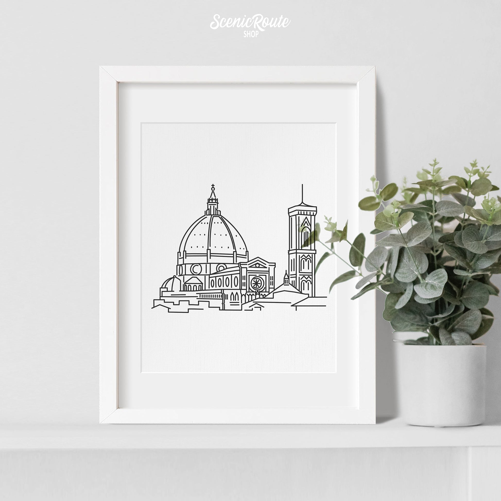 A framed line art drawing of the Florence Duomo with a potted plant
