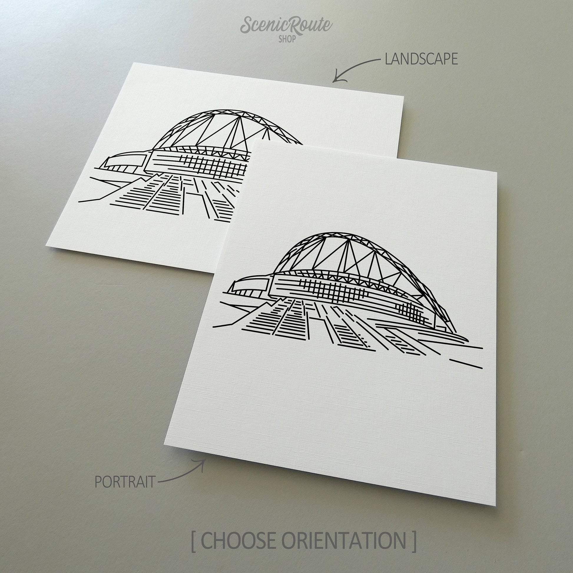 Two line art drawings of Wembley Stadium on white linen paper with a gray background.  The pieces are shown in portrait and landscape orientation for the available art print options.