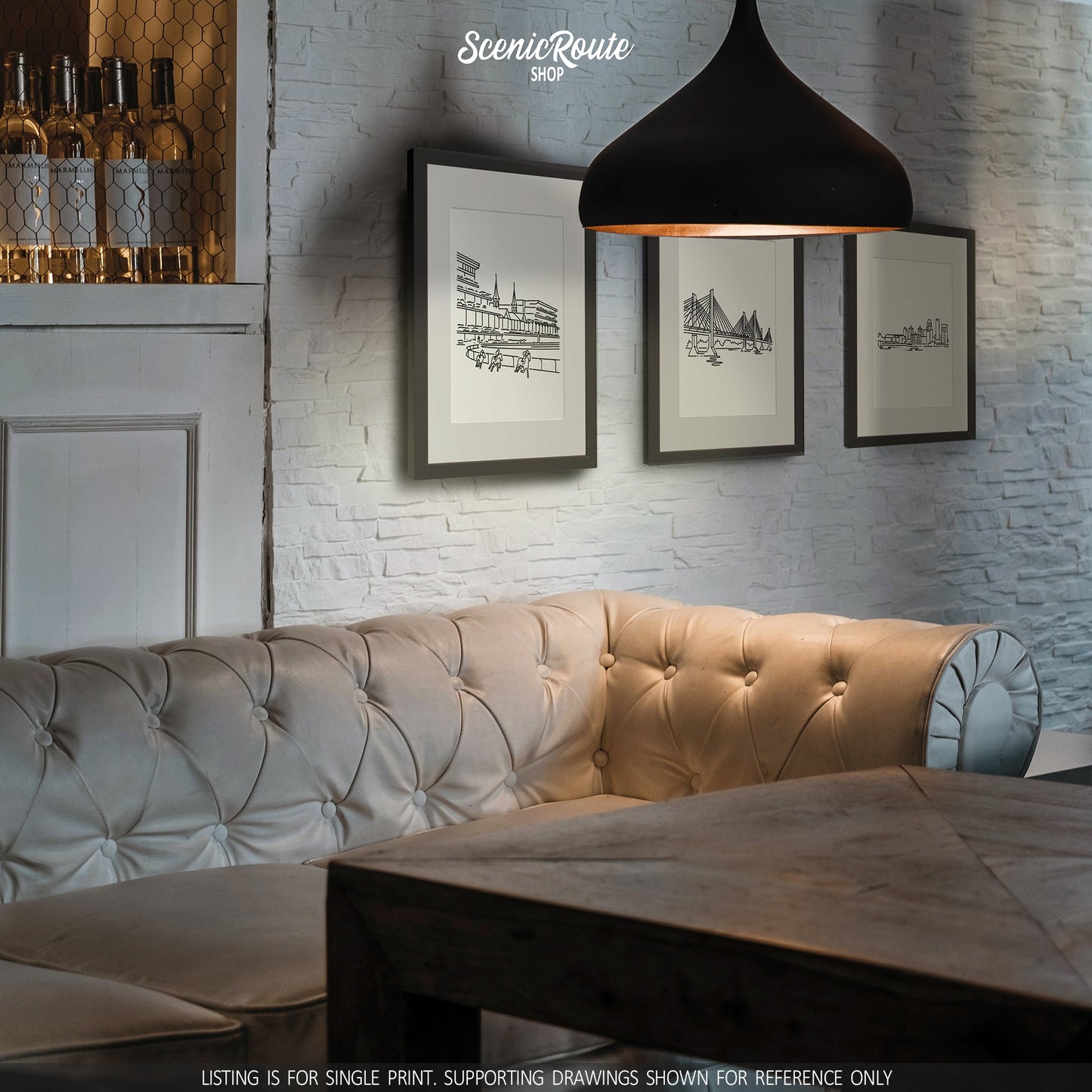 A group of three framed drawings on a wall above a couch. The line art drawings include Churchill Downs, the Abraham Lincoln Bridge, and the Louisville Skyline