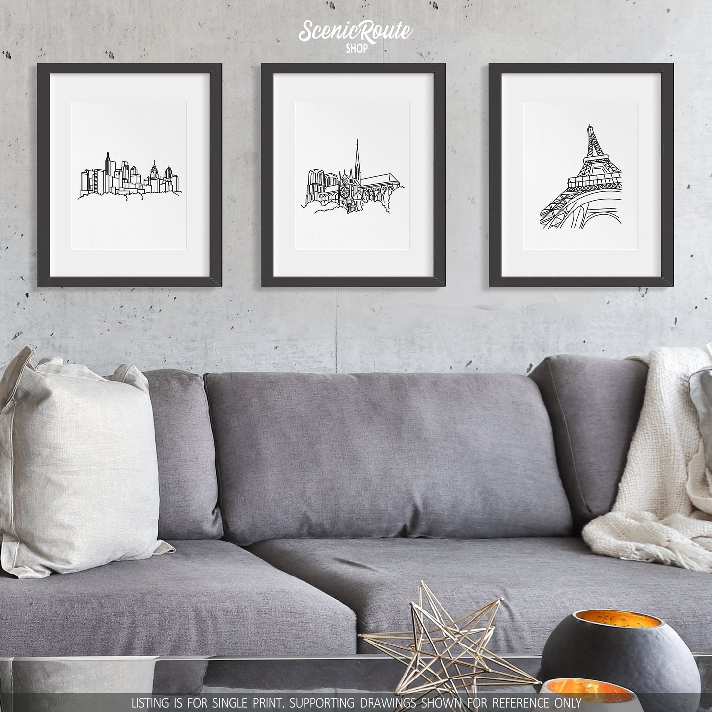 A group of three framed drawings on a wall above a couch. The line art drawings include the Philadelphia Skyline, Notre Dame Cathedral, and Eiffel Tower