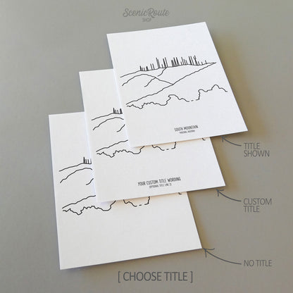 Three line art drawings of South Mountain in Phoenix Arizona on white linen paper with a gray background.  The pieces are shown with title options that can be chosen and personalized.
