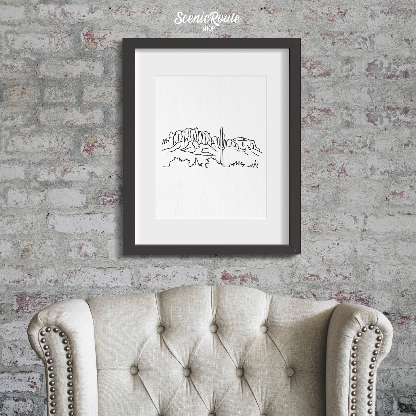 A framed line art drawing of Superstition Mountains hung above a chair