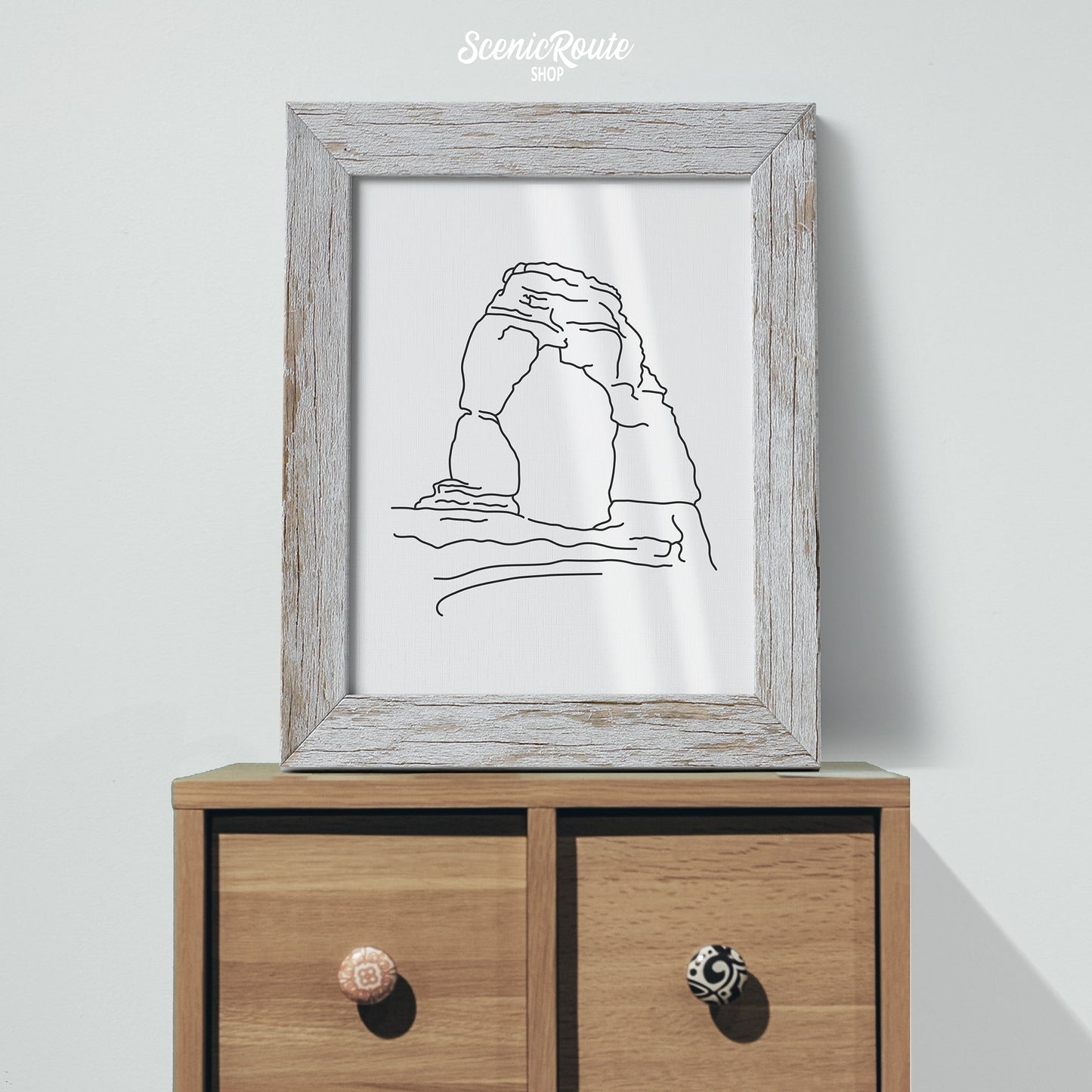A framed line art drawing of Arches National Park on a cabinet