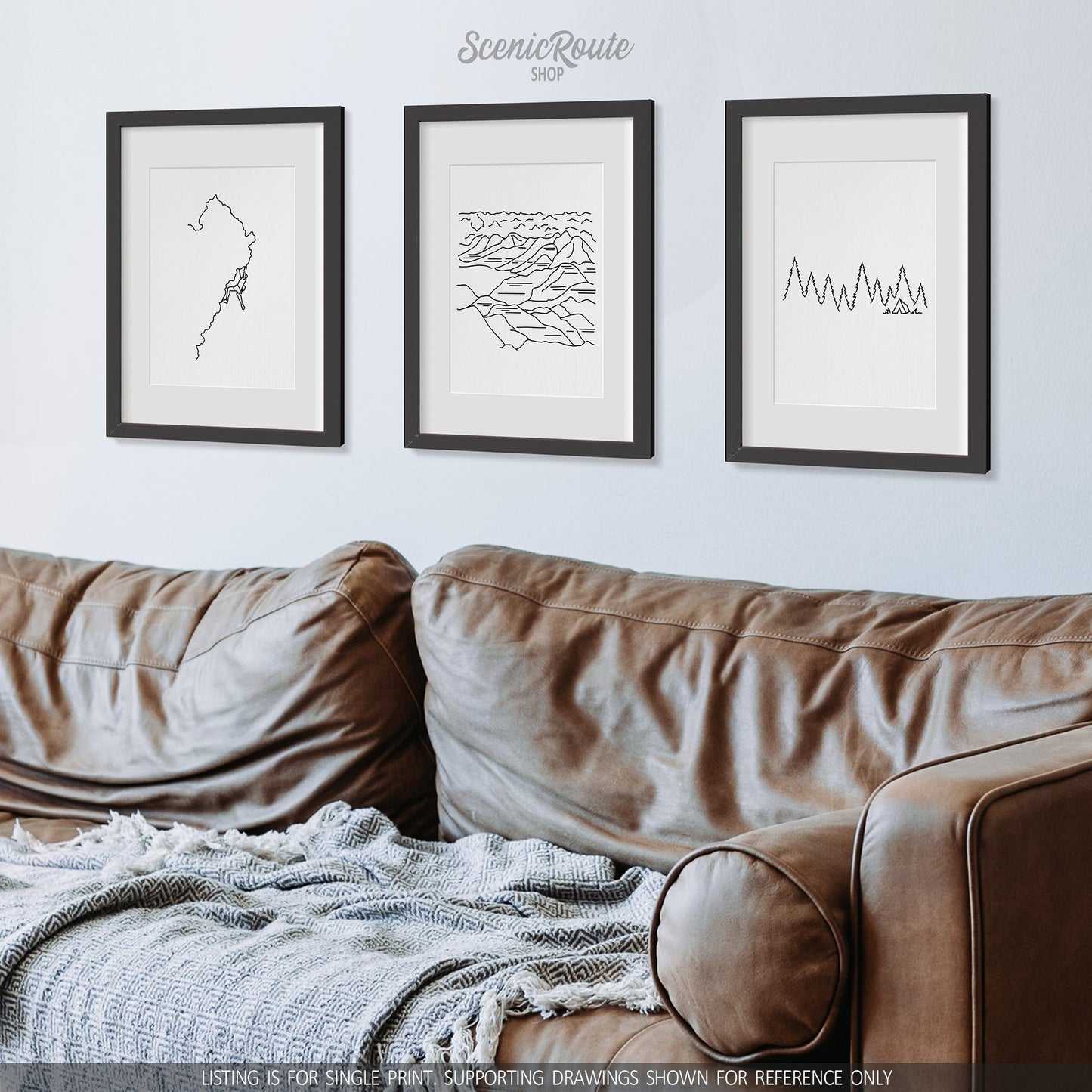 A group of three framed drawings on a wall above a couch. The line art drawings include Rock Climbing, Badlands National Park, and Camping