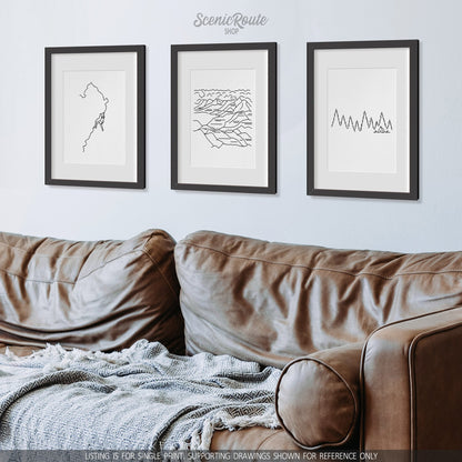 A group of three framed drawings on a wall above a couch. The line art drawings include Rock Climbing, Badlands National Park, and Camping