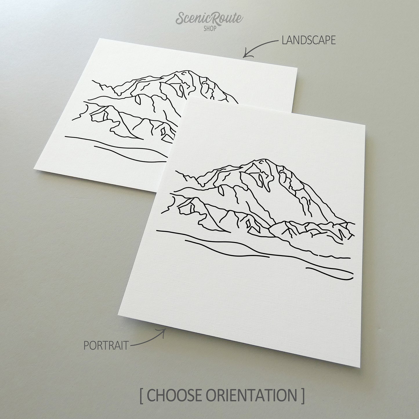 Two line art drawings of Denali National Park on white linen paper with a gray background.  The pieces are shown in portrait and landscape orientation for the available art print options.