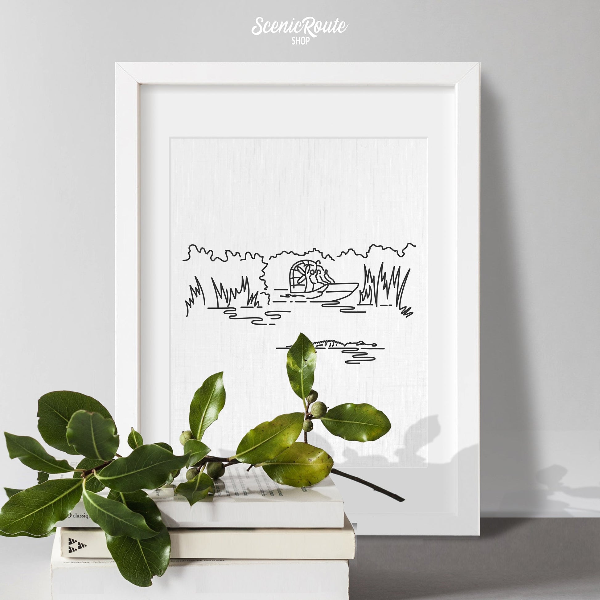 A framed line art drawing of Everglades National Park with books and a plant sprig