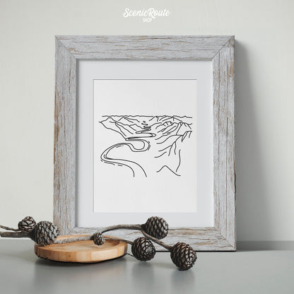 A framed line art drawing of Gates of the Arctic National Park with pinecones