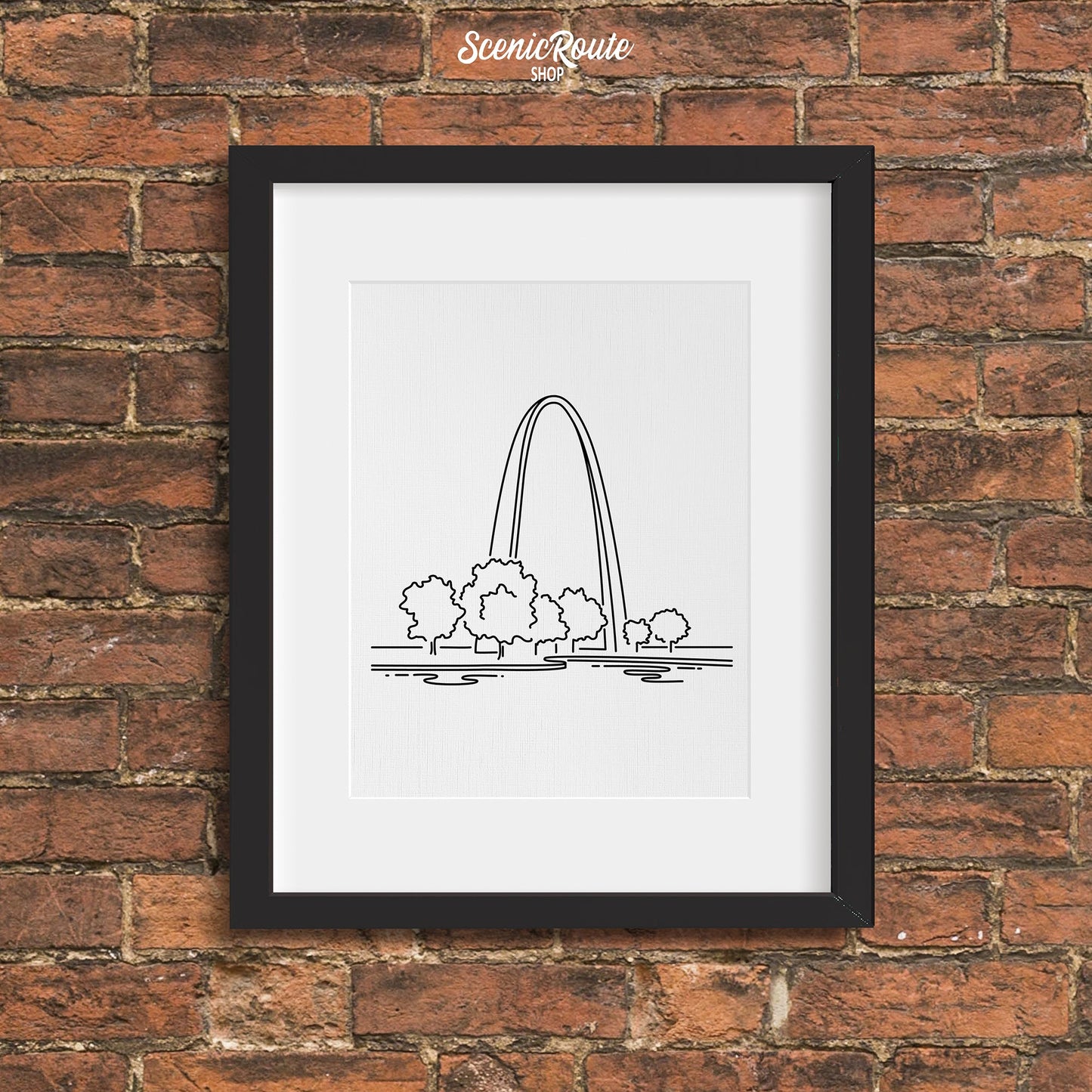 A framed line art drawing of Gateway Arch National Park on a brick wall