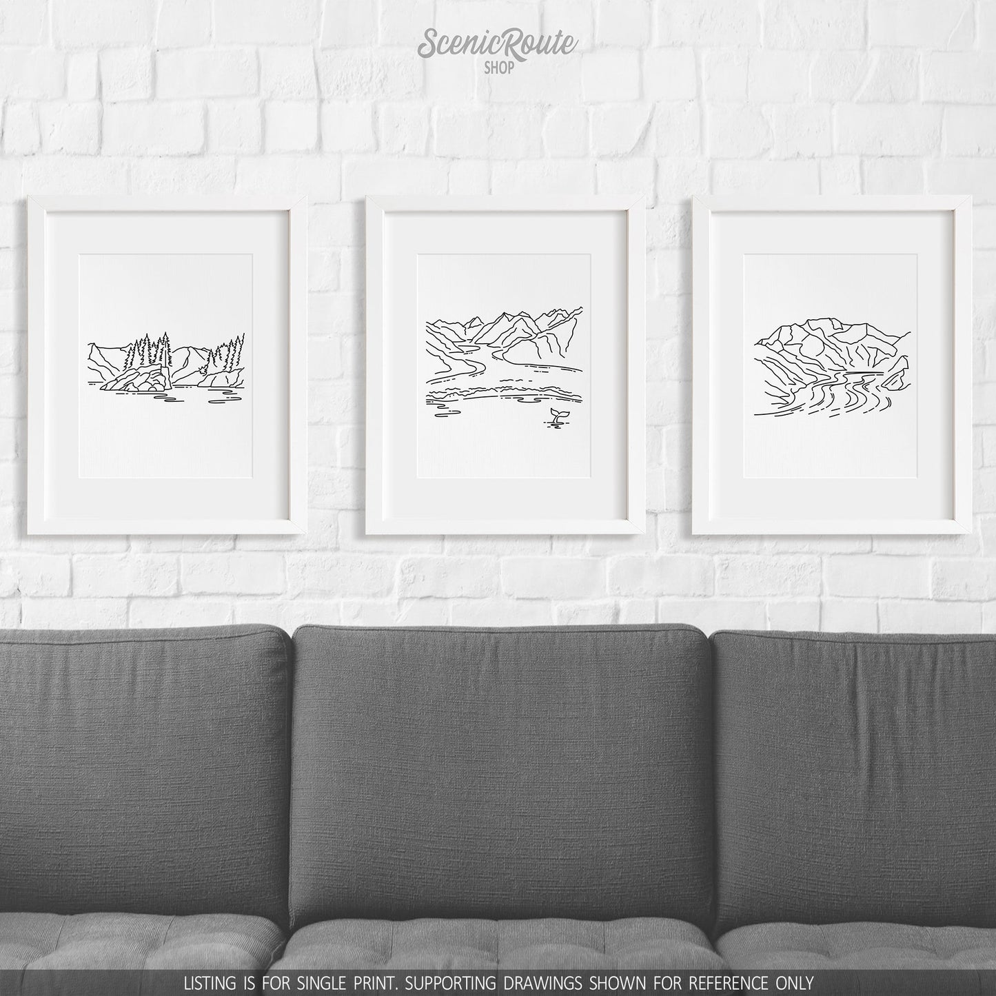 A group of three framed drawings on a wall above a couch. The line art drawings include Kenai Fjords National Park, Glacier Bay National Park, and Wrangell Saint Elias National Park