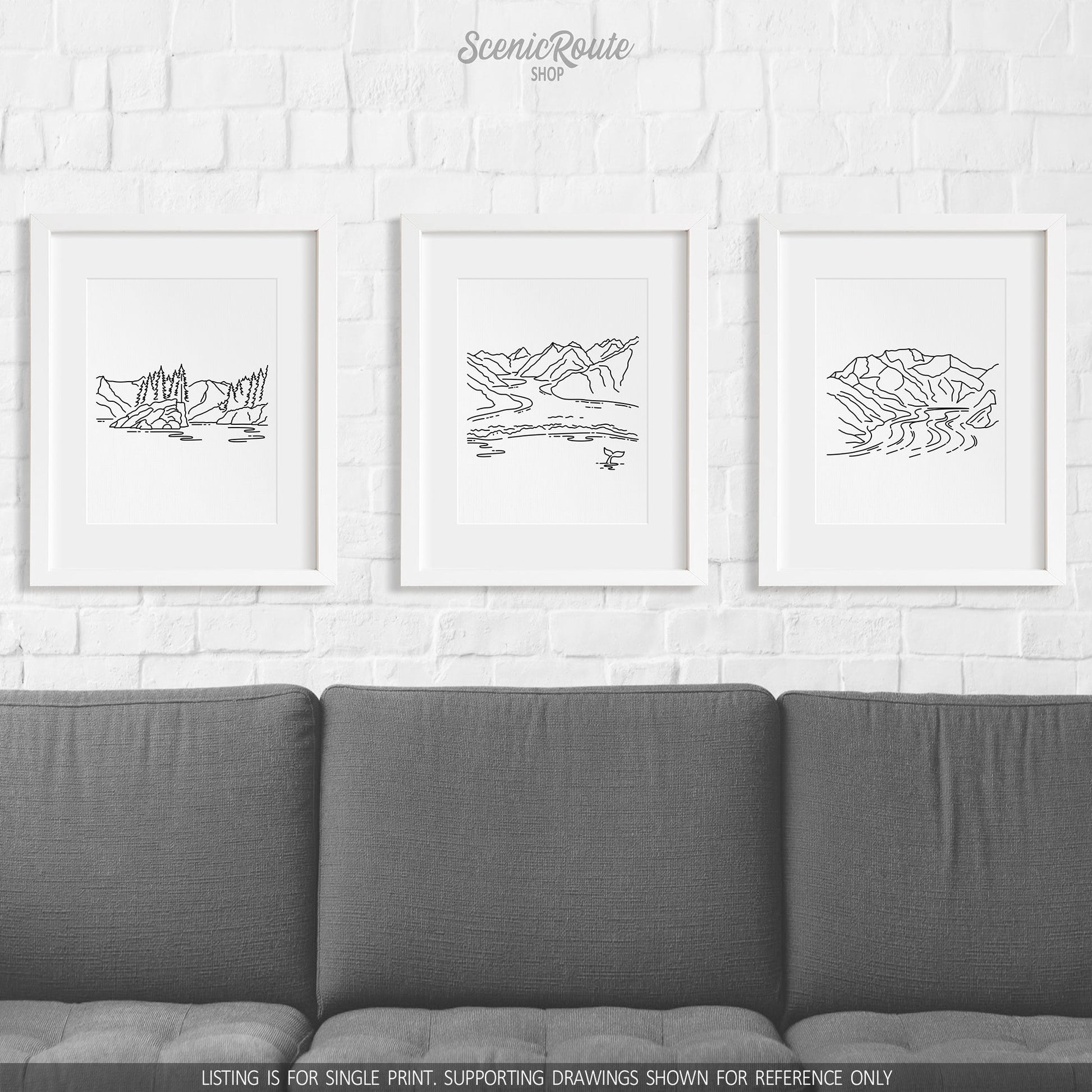 A group of three framed drawings on a wall above a couch. The line art drawings include Kenai Fjords National Park, Glacier Bay National Park, and Wrangell Saint Elias National Park