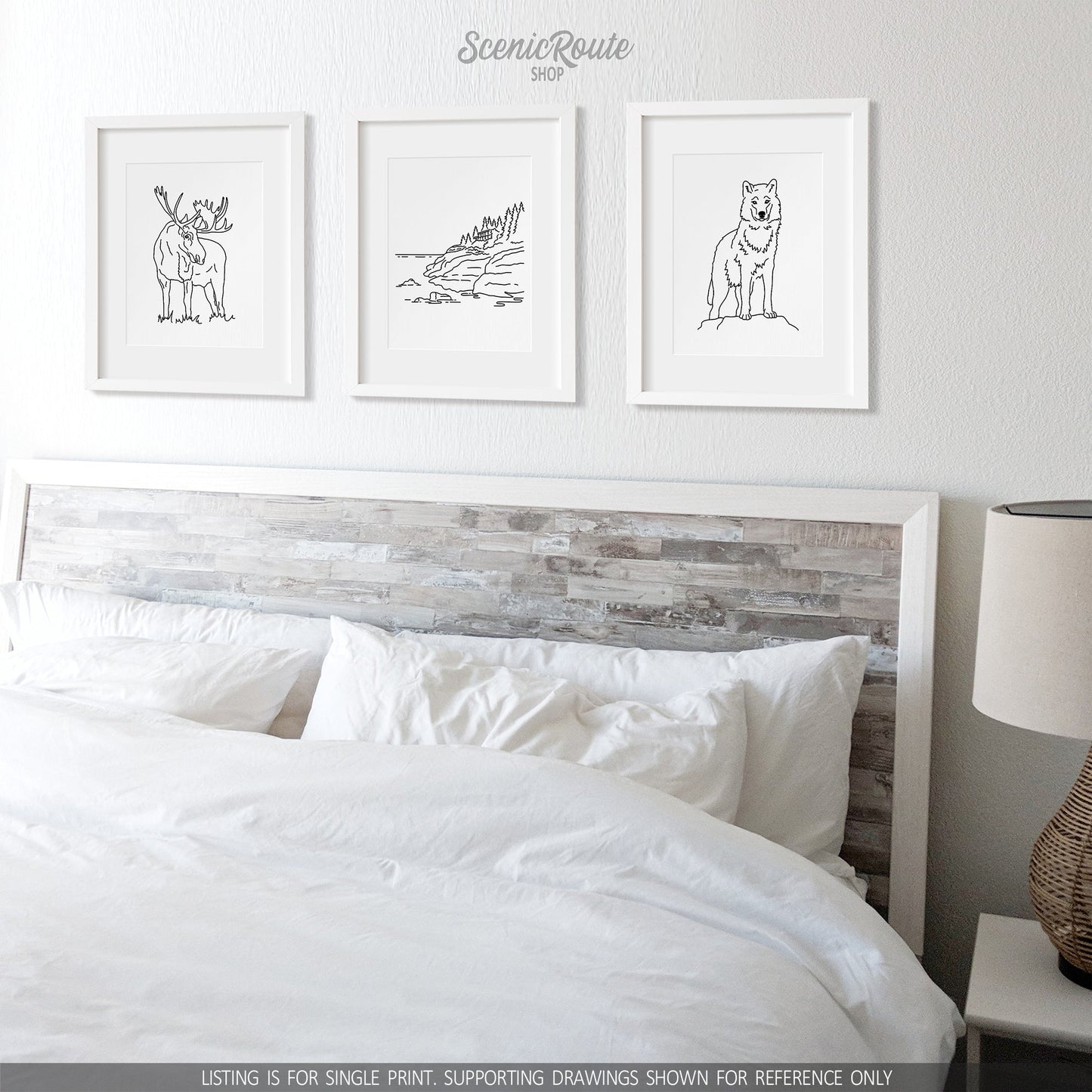 A group of three framed drawings on a white wall above a bed. The line art drawings include a Moose, Isle Royale National Park, and a Wolf