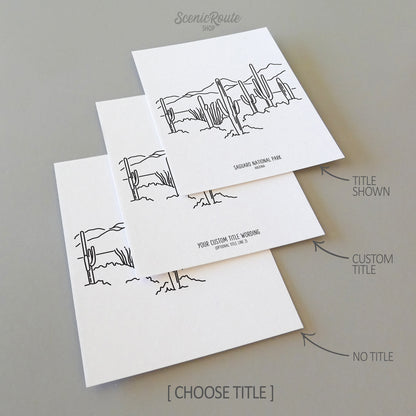 Three line art drawings of Saguaro National Park on white linen paper with a gray background. The pieces are shown with title options that can be chosen and personalized.