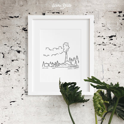 A framed line art drawing of Yellowstone National Park hanging above a tropical plant