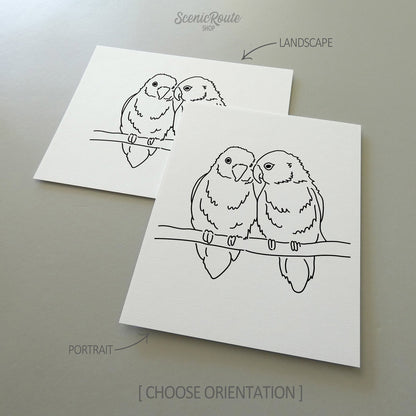 Two line art drawings of a Love Birds on white linen paper with a gray background.  The pieces are shown in portrait and landscape orientation for the available art print options.
