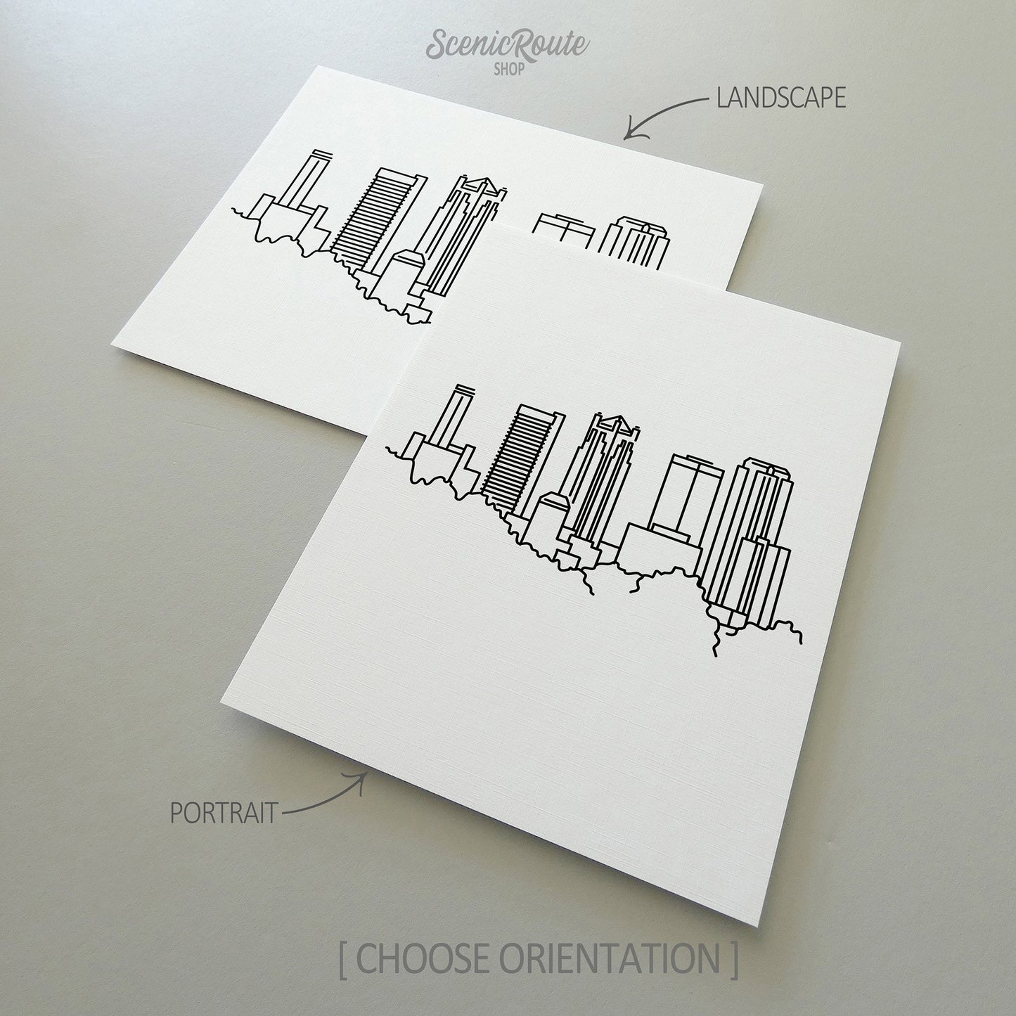 Two line art drawings of the Birmingham Skyline on white linen paper with a gray background. The pieces are shown in portrait and landscape orientation for the available art print options.