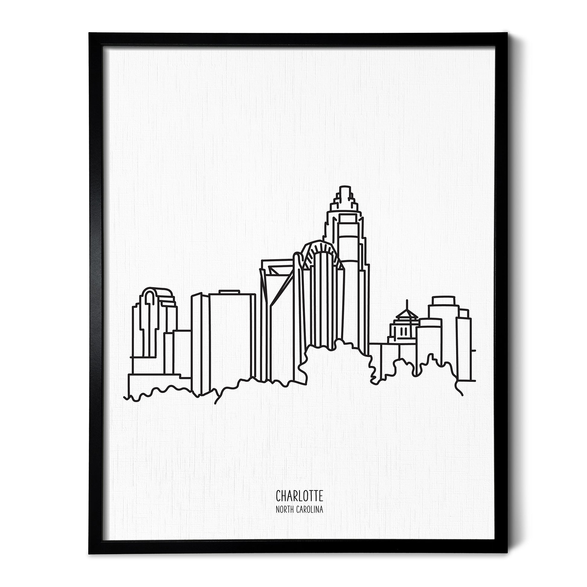 A line art drawing of the Charlotte North Carolina Skyline on white linen paper in a thin black picture frame