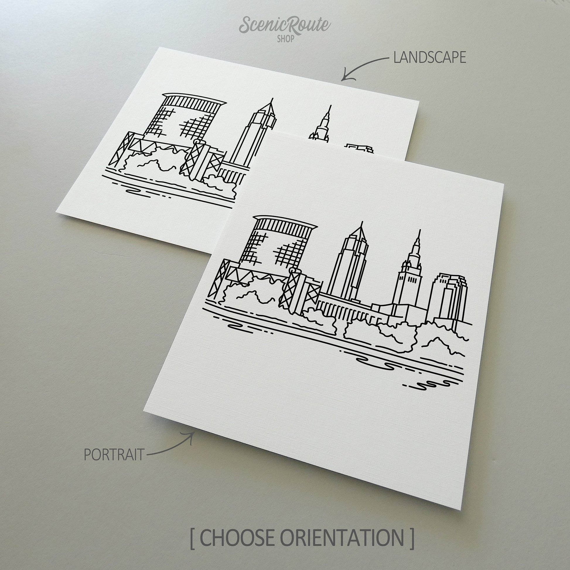Two line art drawings of the Cleveland Skyline on white linen paper with a gray background.  The pieces are shown in portrait and landscape orientation for the available art print options.