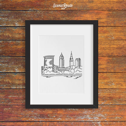 A framed line art drawing of the Cleveland Skyline on a wood wall