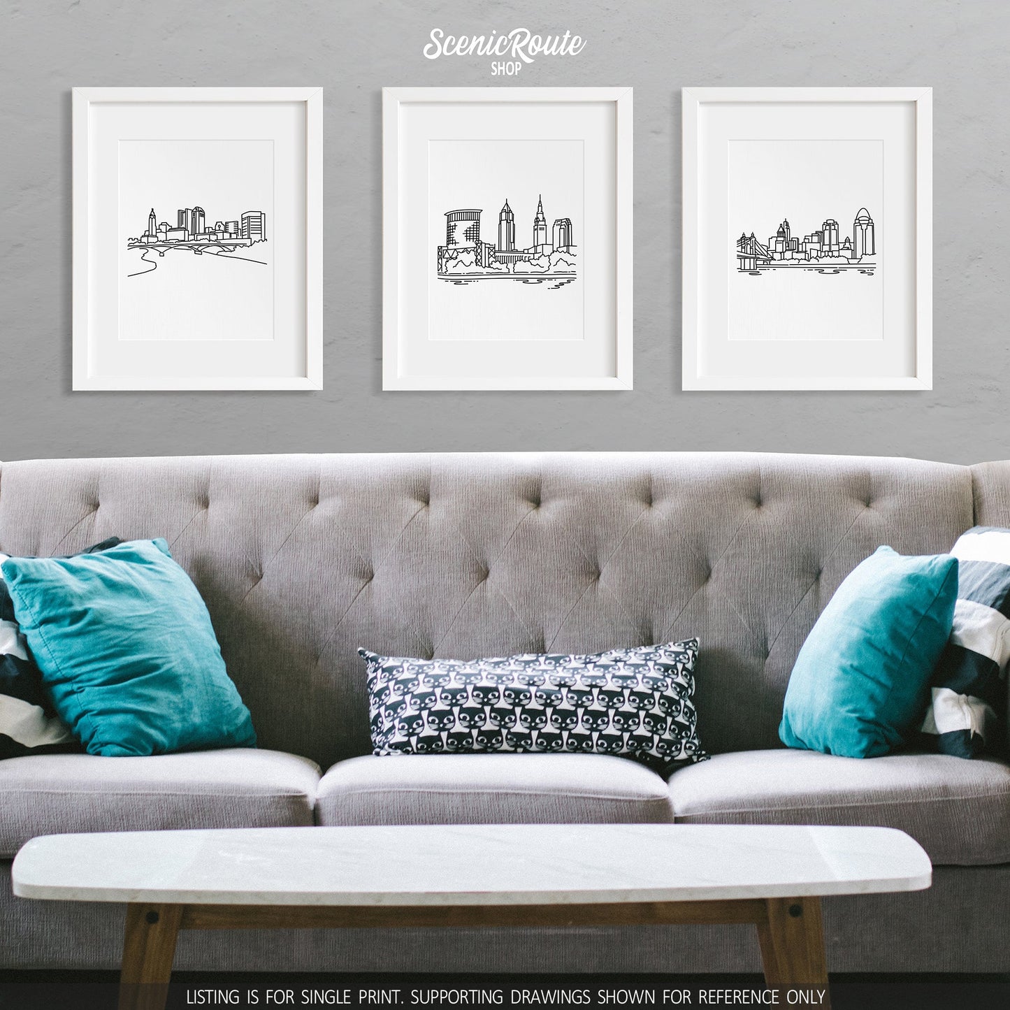A group of three framed drawings on a wall above a couch with pillows. The line art drawings include the Columbus Skyline, Cleveland Skyline, and Cincinnati Skyline