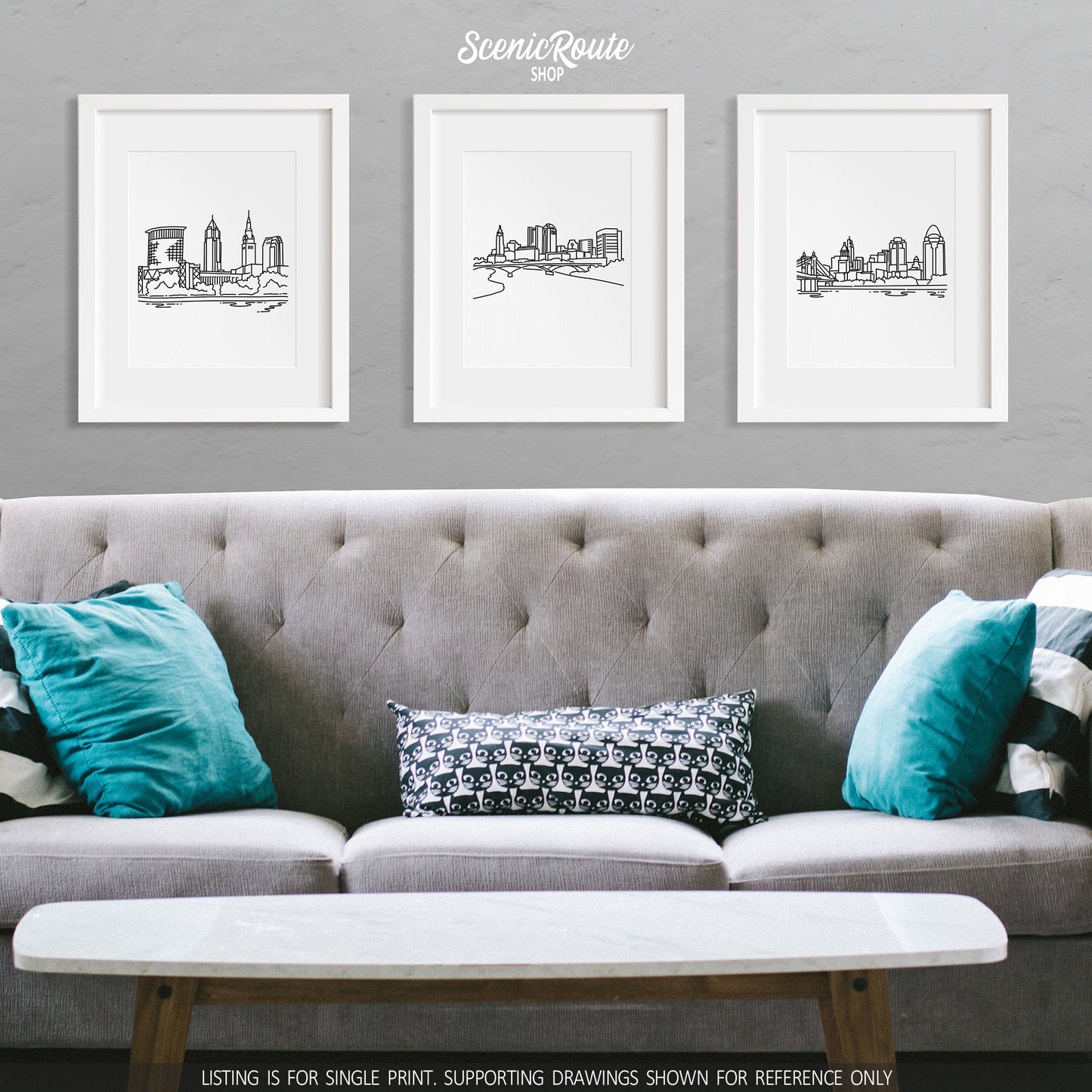 A group of three framed drawings on a wall above a couch with pillows. The line art drawings include the Cleveland Skyline, Columbus Skyline, and Cincinnati Skyline