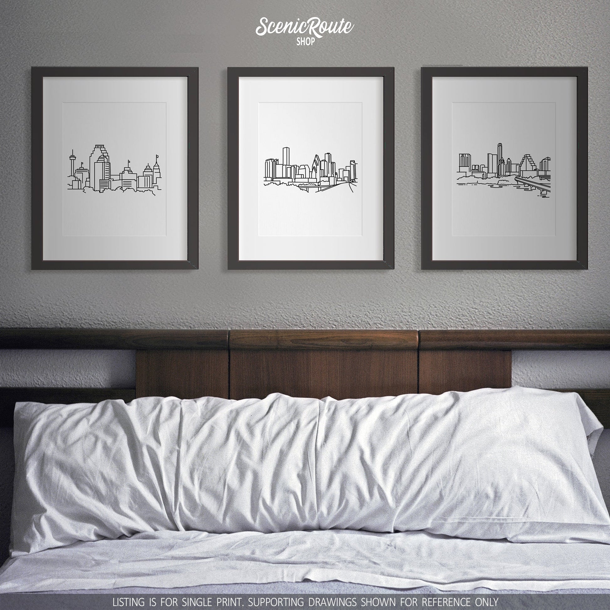 A group of three framed drawings on a white wall above a bed. The line art drawings include the San Antonio Skyline, Houston Skyline, and Austin Skyline