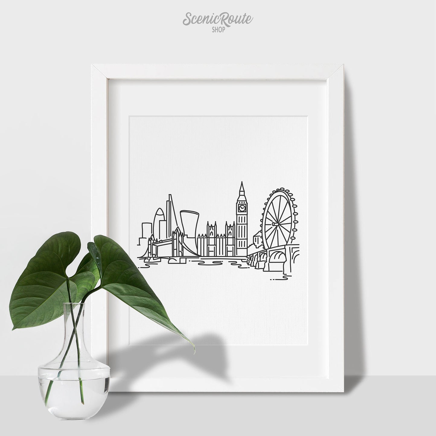 A framed line art drawing of the London Skyline with a vase