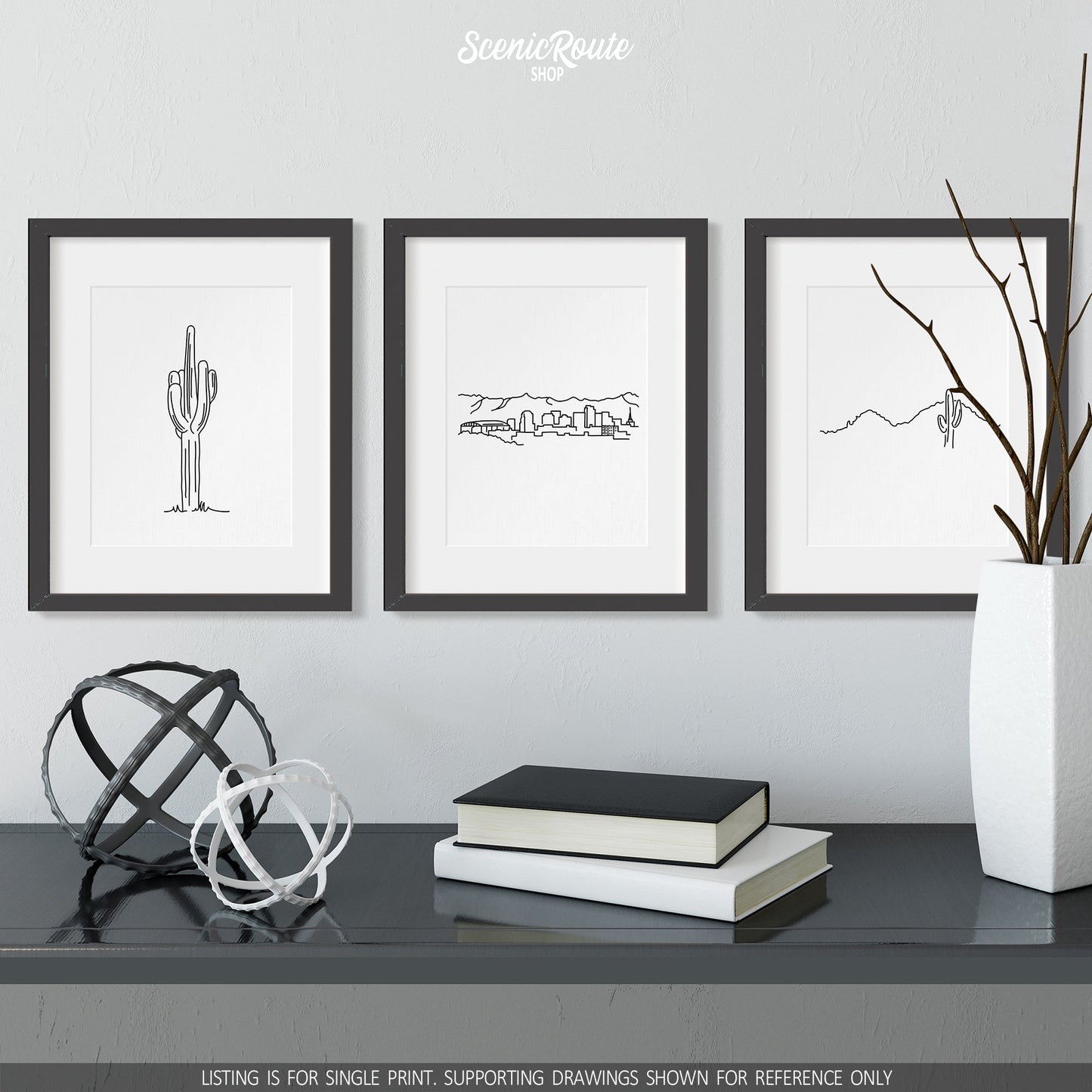 A group of three framed drawings on a wall above a dresser with books and figurines. The line art drawings include a Saguaro Cactus, the Phoenix Skyline, and Camelback Mountain
