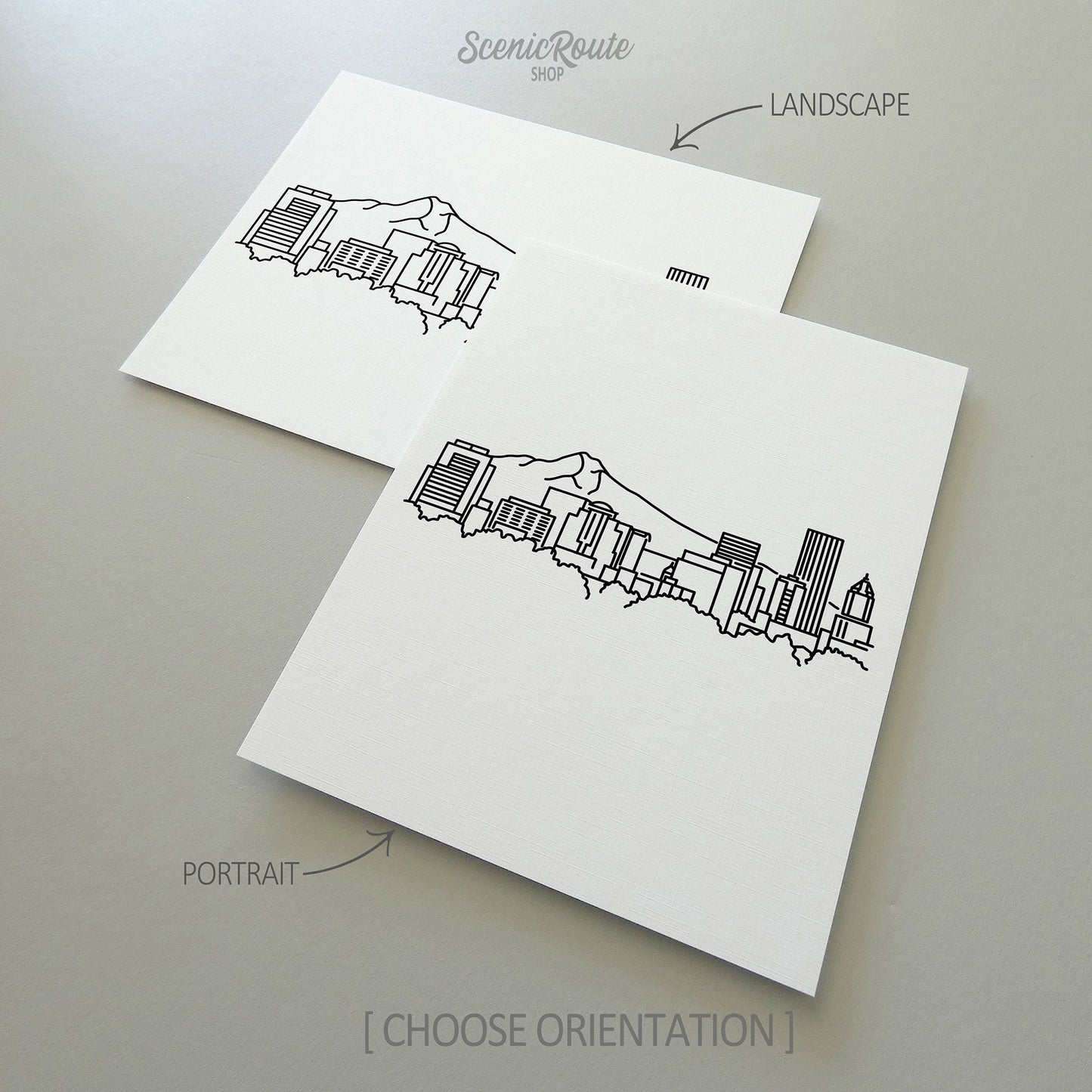 Two line art drawings of the Portland Skyline on white linen paper with a gray background. The pieces are shown in portrait and landscape orientation for the available art print options.