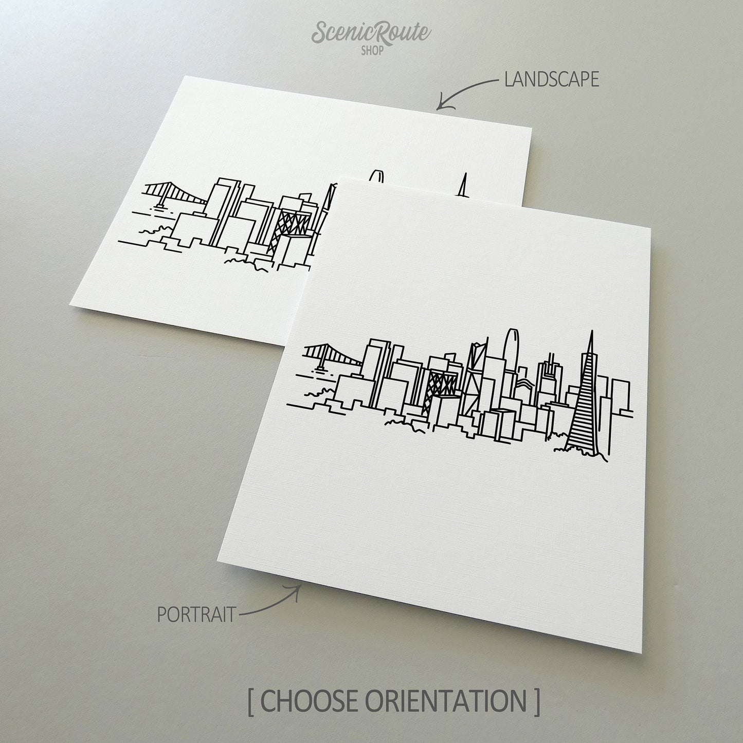 Two line art drawings of the San Francisco Skyline on white linen paper with a gray background. The pieces are shown in portrait and landscape orientation for the available art print options.